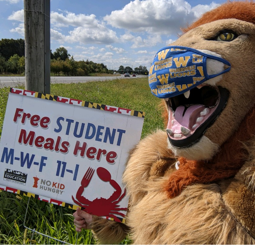 Picture of the Walkersville High School mascot holding the "free meals here" sign